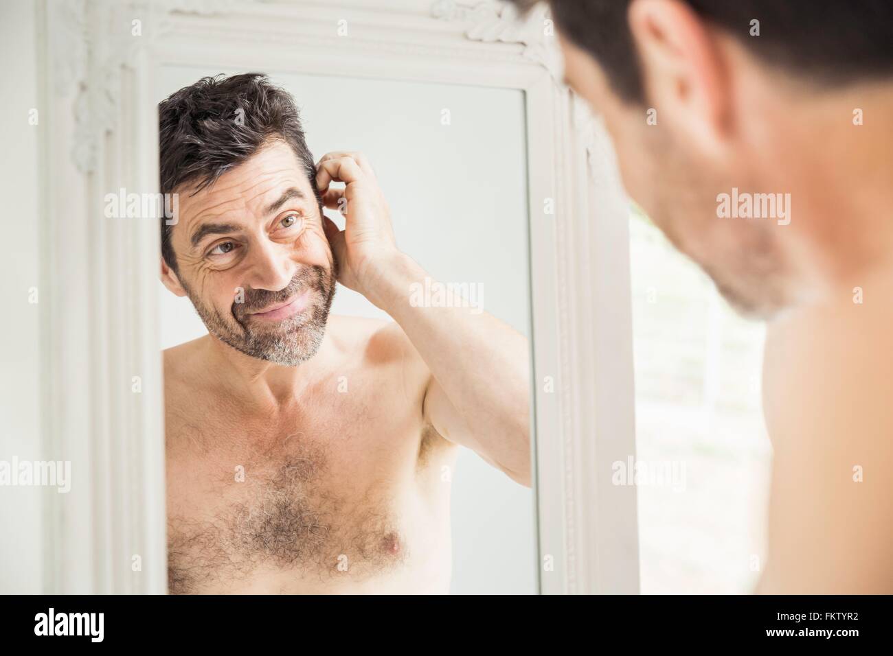 Happy mature man looking at himself in mirror at home Stock Photo