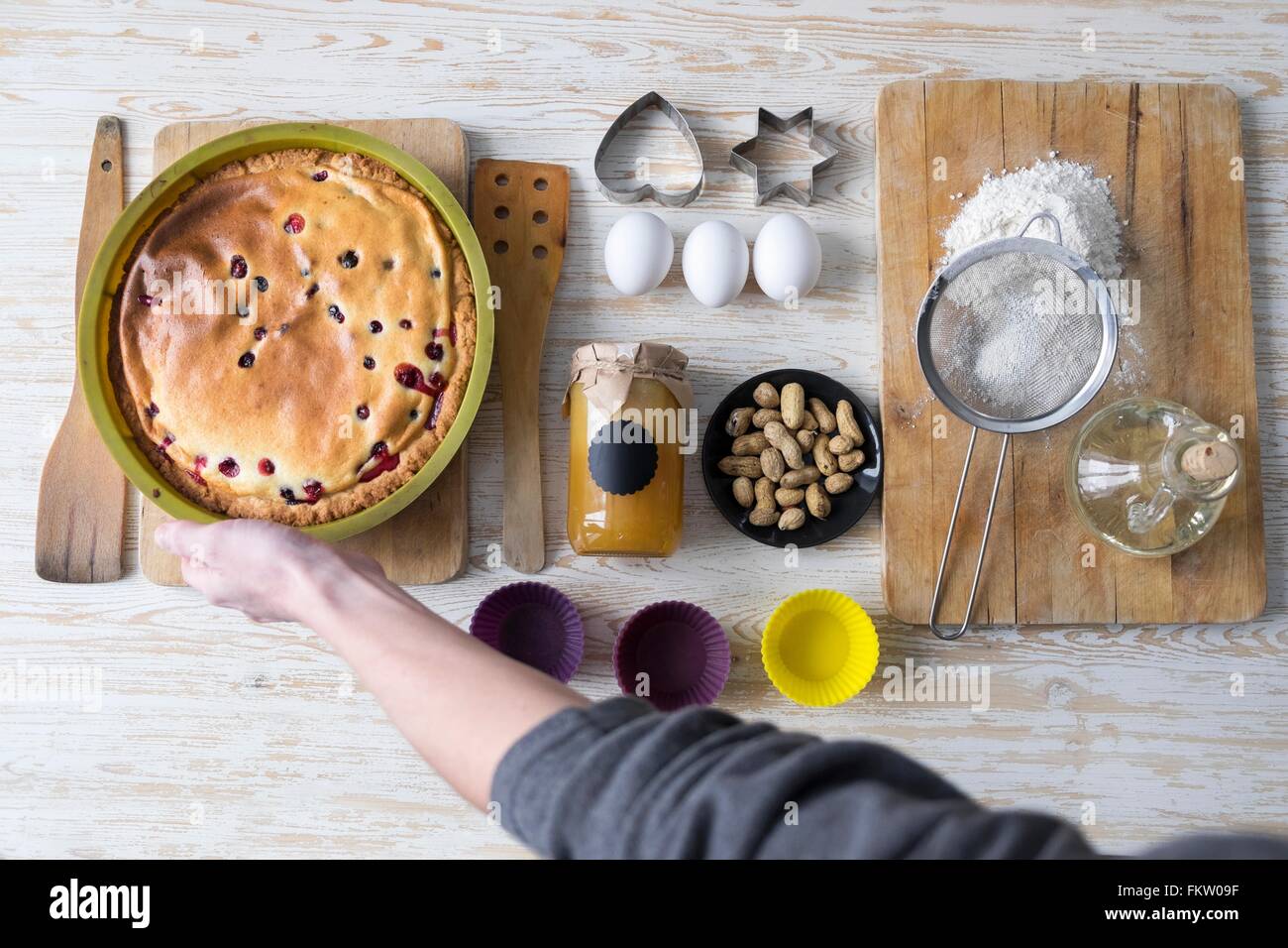 Overhead view of female hand picking up baked cake at kitchen counter Stock Photo