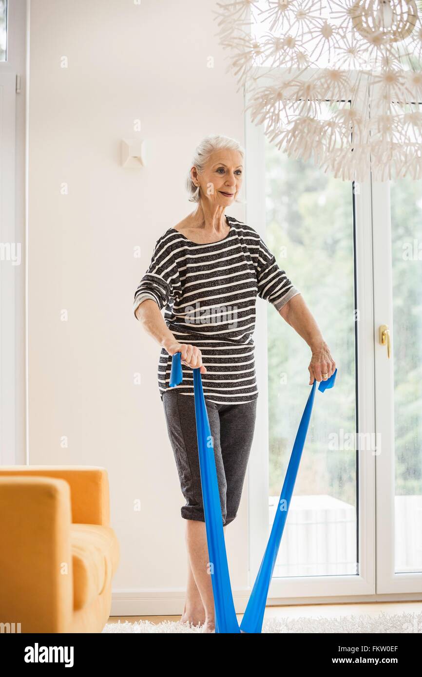 Senior woman exercising in living room pulling resistance band Stock Photo