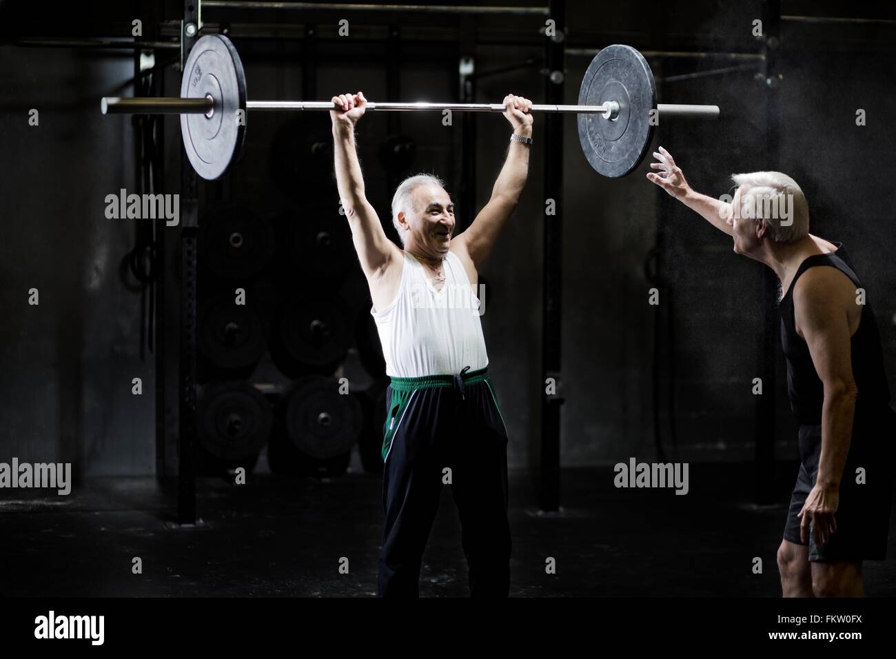 Senior men training with barbell in dark gym Stock Photo