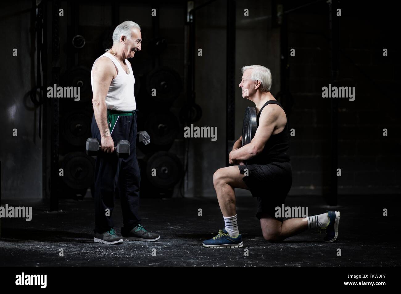 Senior men preparing to weightlift in dark gym Stock Photo