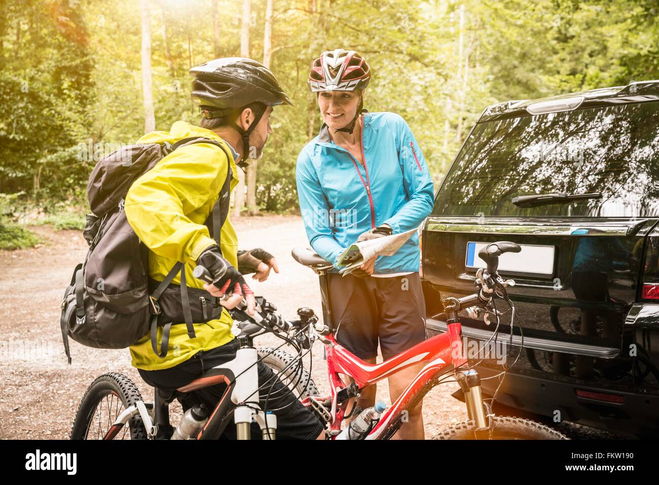 Mature mountain biking couple checking map in forest car park Stock Photo