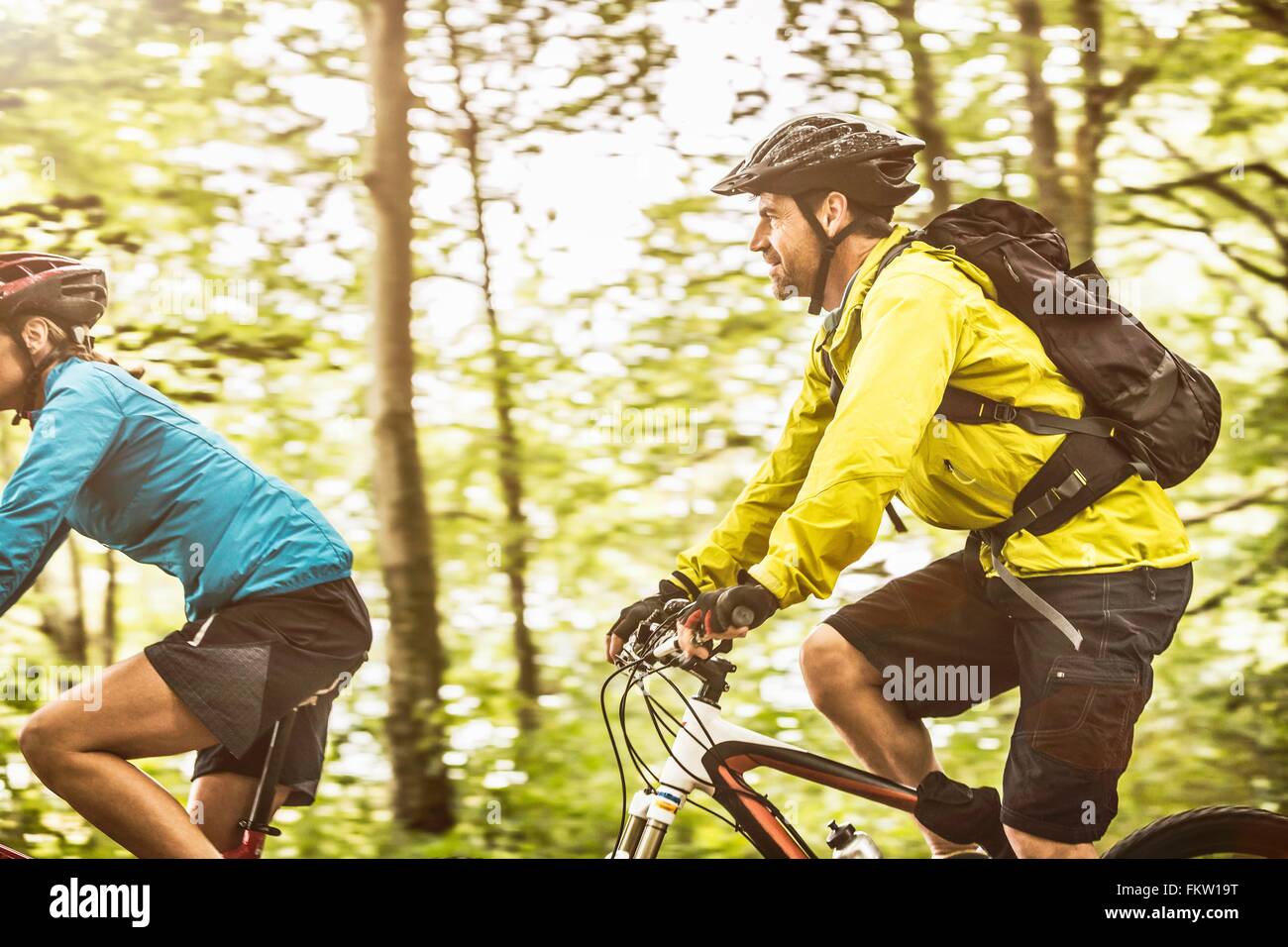 Mature mountain biking couple speed cycling in forest Stock Photo