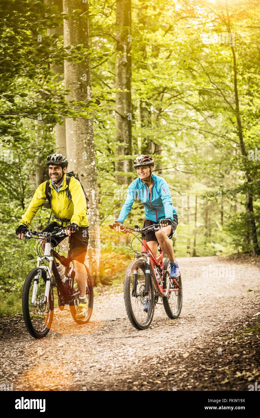 Happy mature mountain biking couple cycling on forest trail Stock Photo