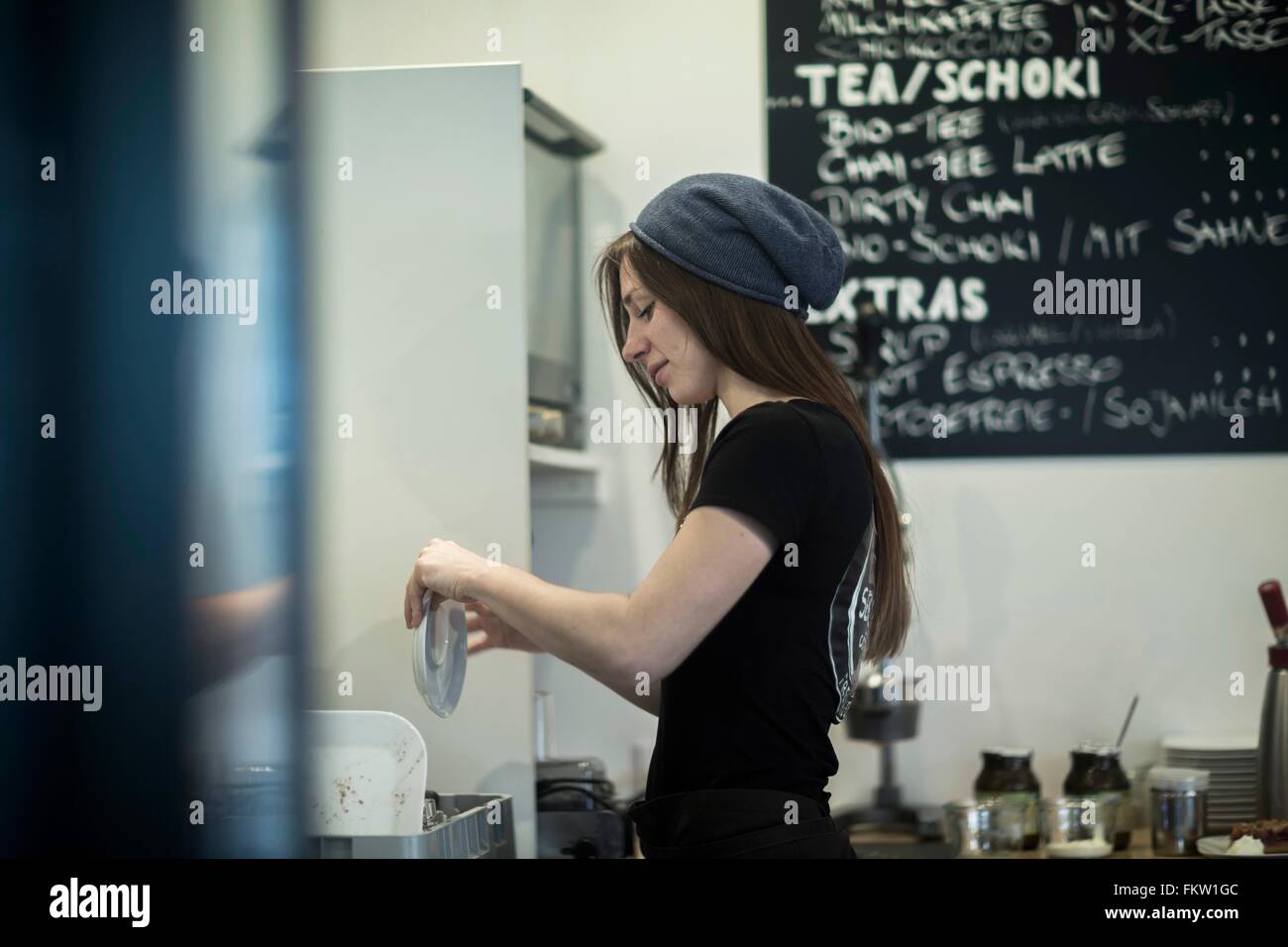 Young female waitress working in cafe kitchen Stock Photo