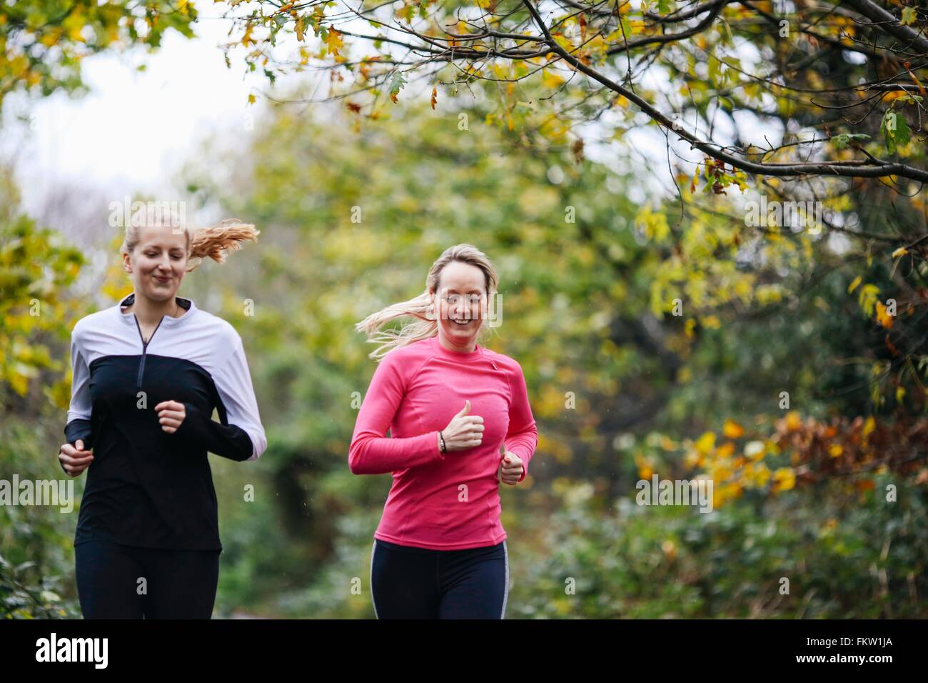 Teenage girl and woman running in park Stock Photo