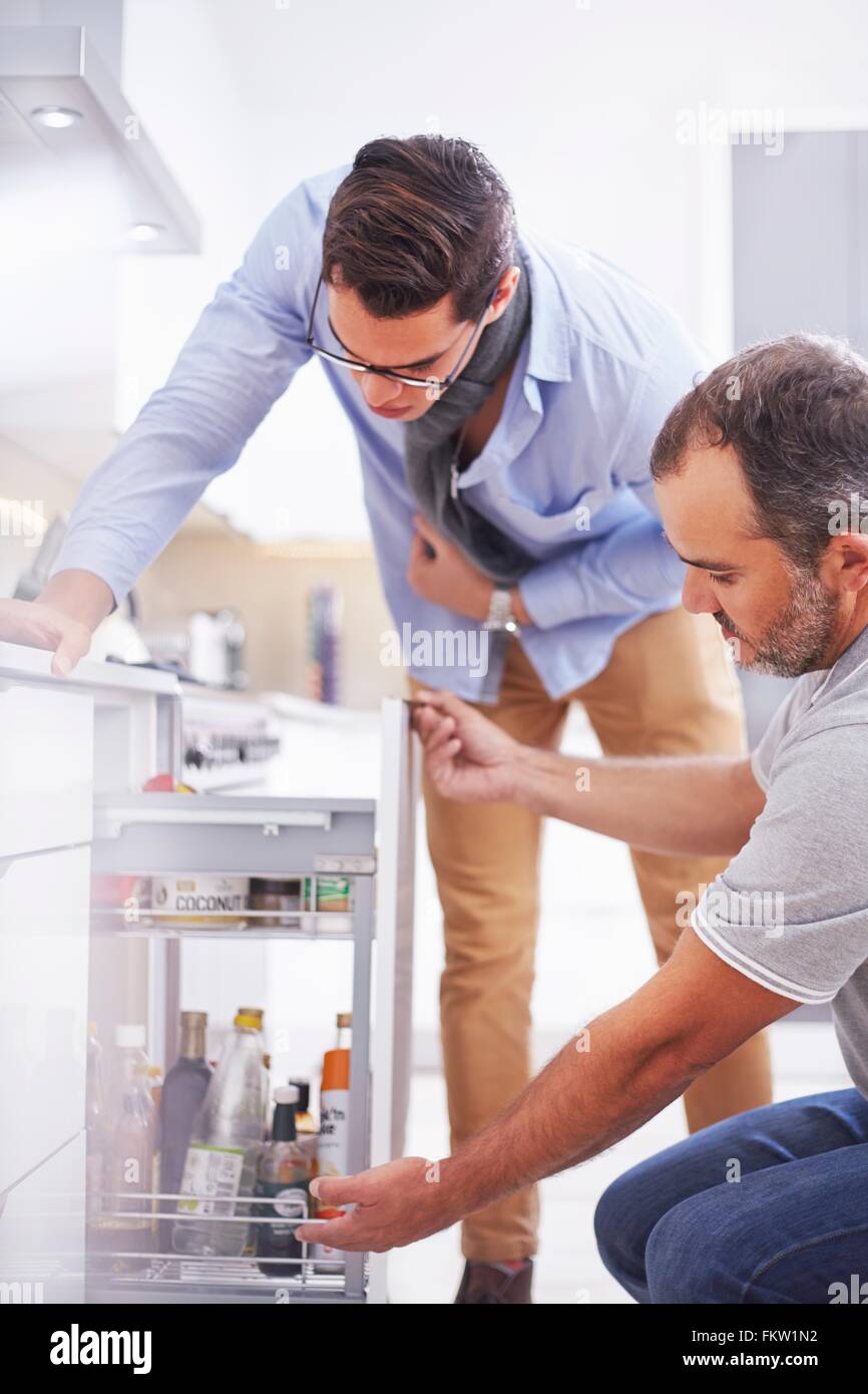 Joiner repairing drawer in young mans kitchen Stock Photo