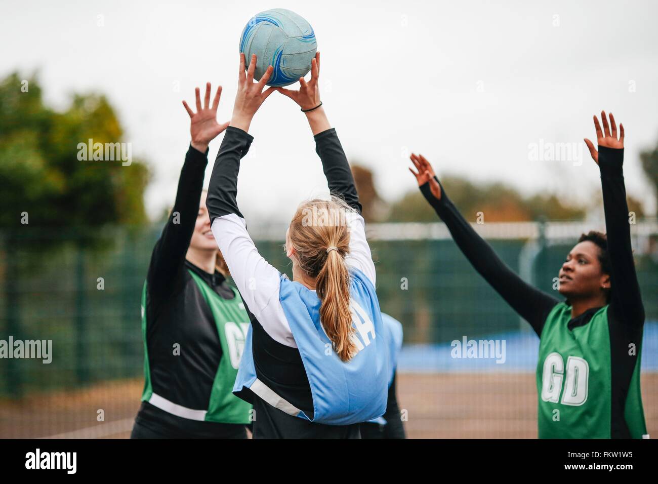 Female netball teams throwing ball on netball court Stock Photo