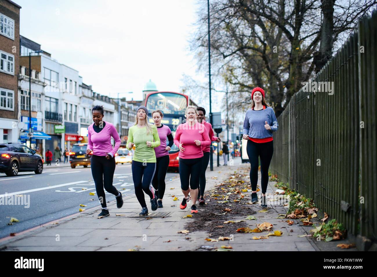 Five female runners running on city sidewalk Stock Photo