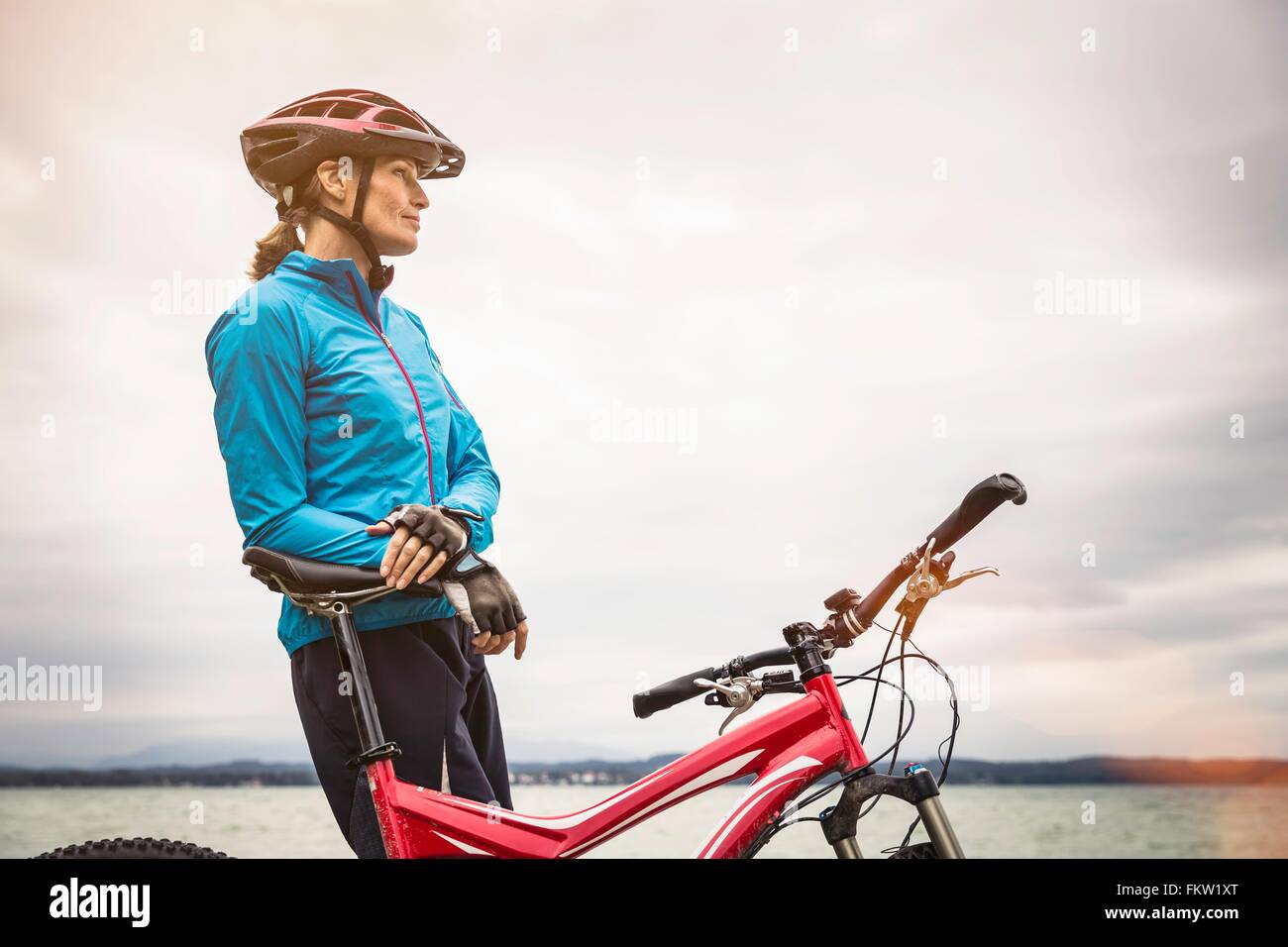 Mature female mountain biker looking out from lakeside Stock Photo