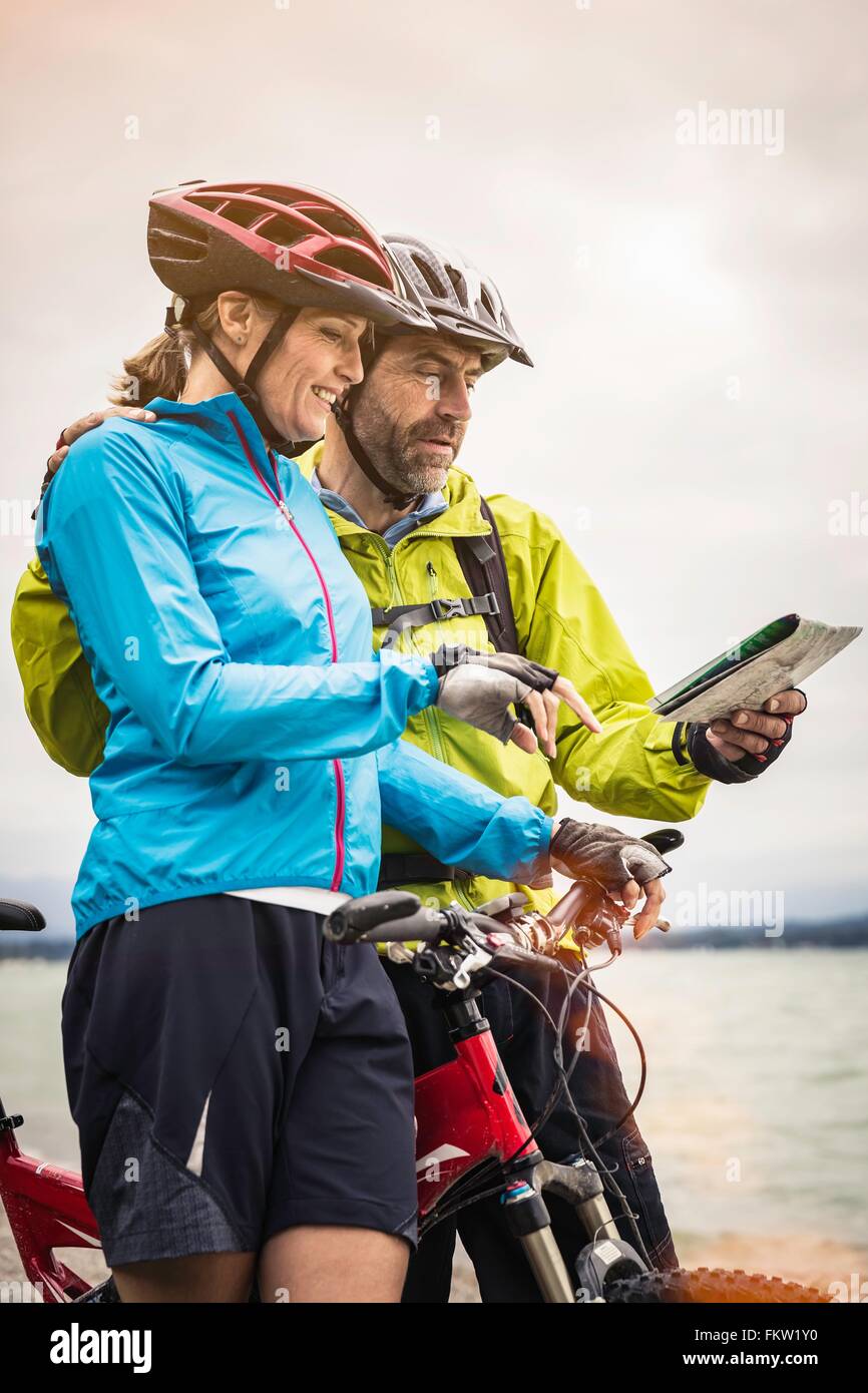 Mature mountain biking couple reading map at lakeside Stock Photo