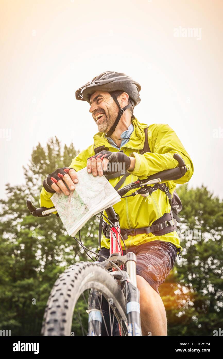 Low angle view of mature male mountain biker with map Stock Photo