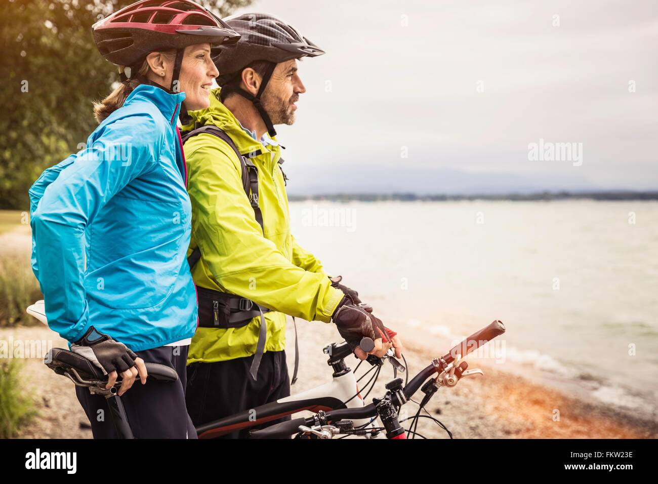 Mature mountain biking couple looking out from lakeside Stock Photo