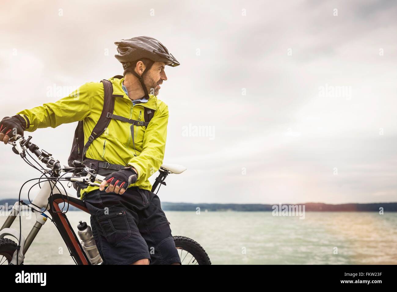 Mature male mountain biker looking out from lakeside Stock Photo