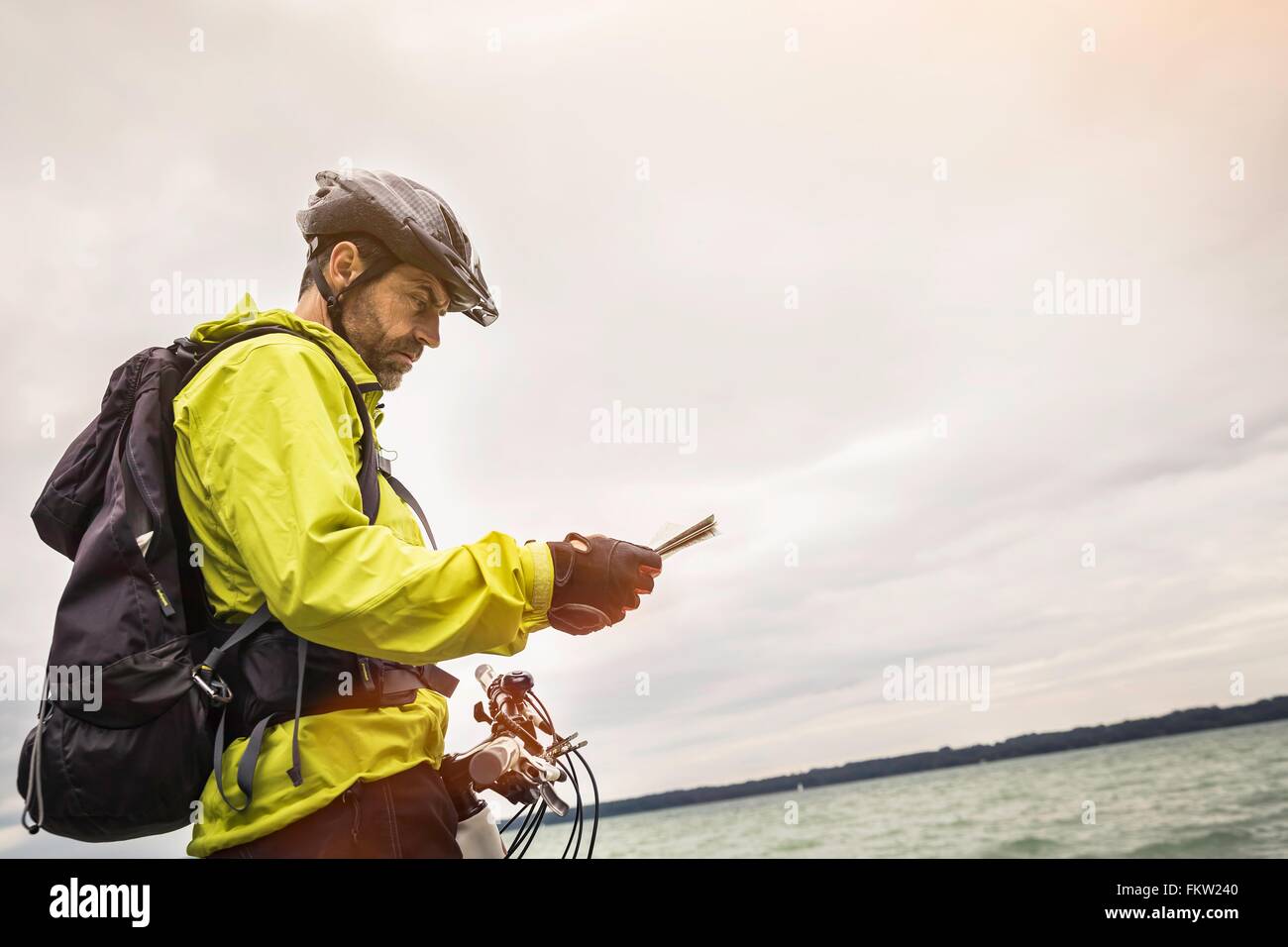 Male mountain biker reading map at lakeside Stock Photo