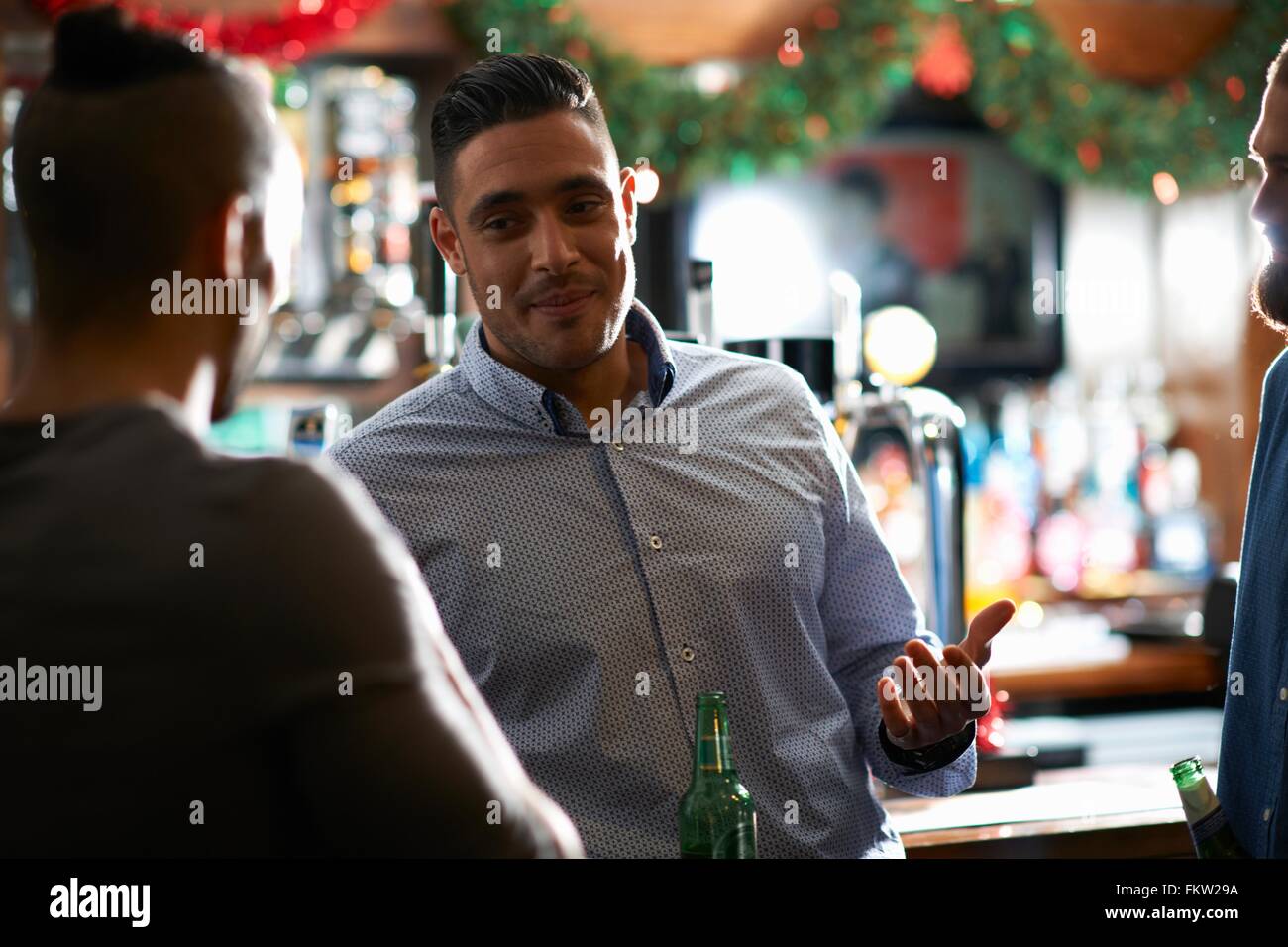 Man leaning against counter in public house talking to friend Stock Photo