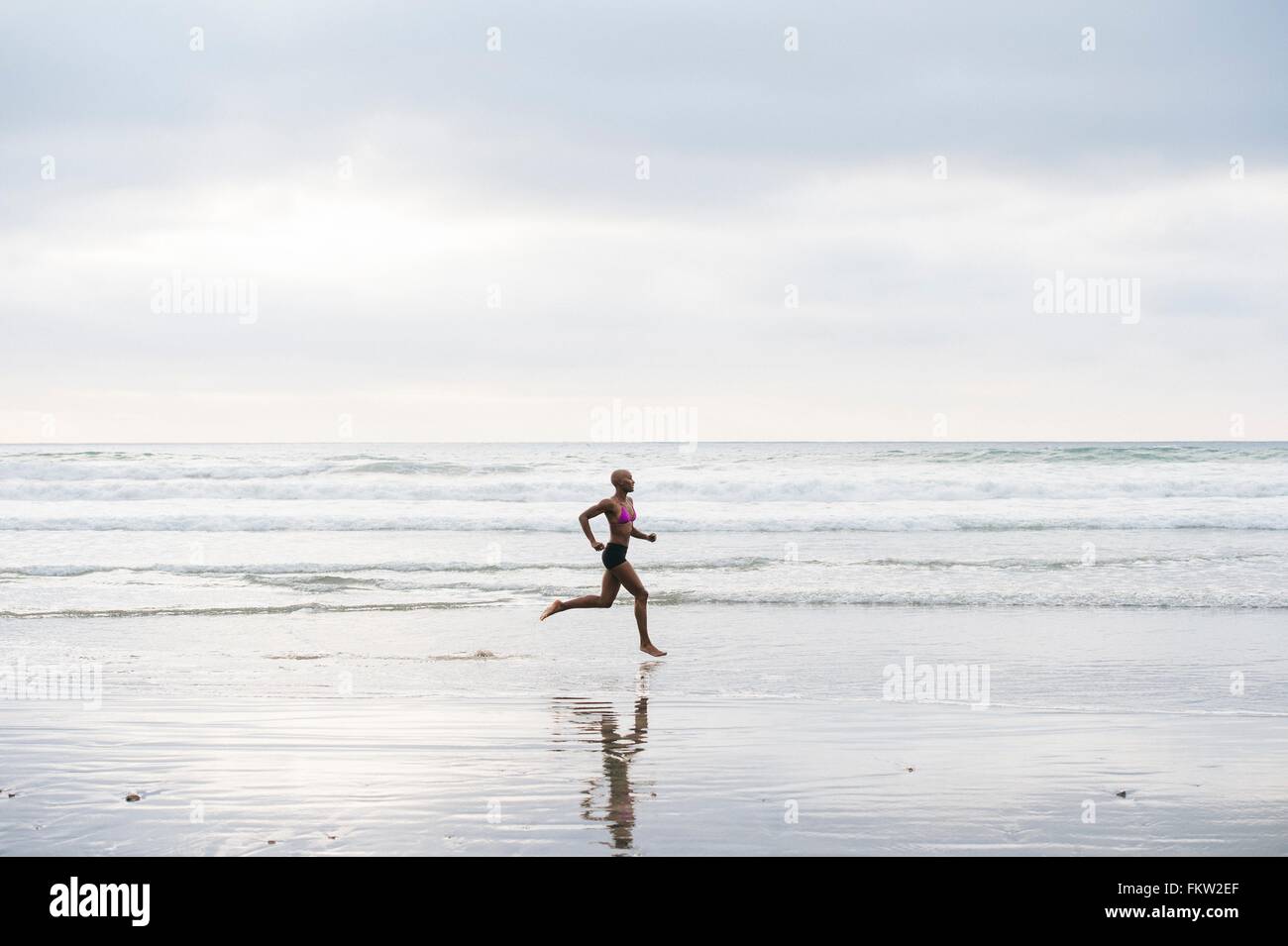 Woman in bikini jogging on beach Stock Photo Alamy