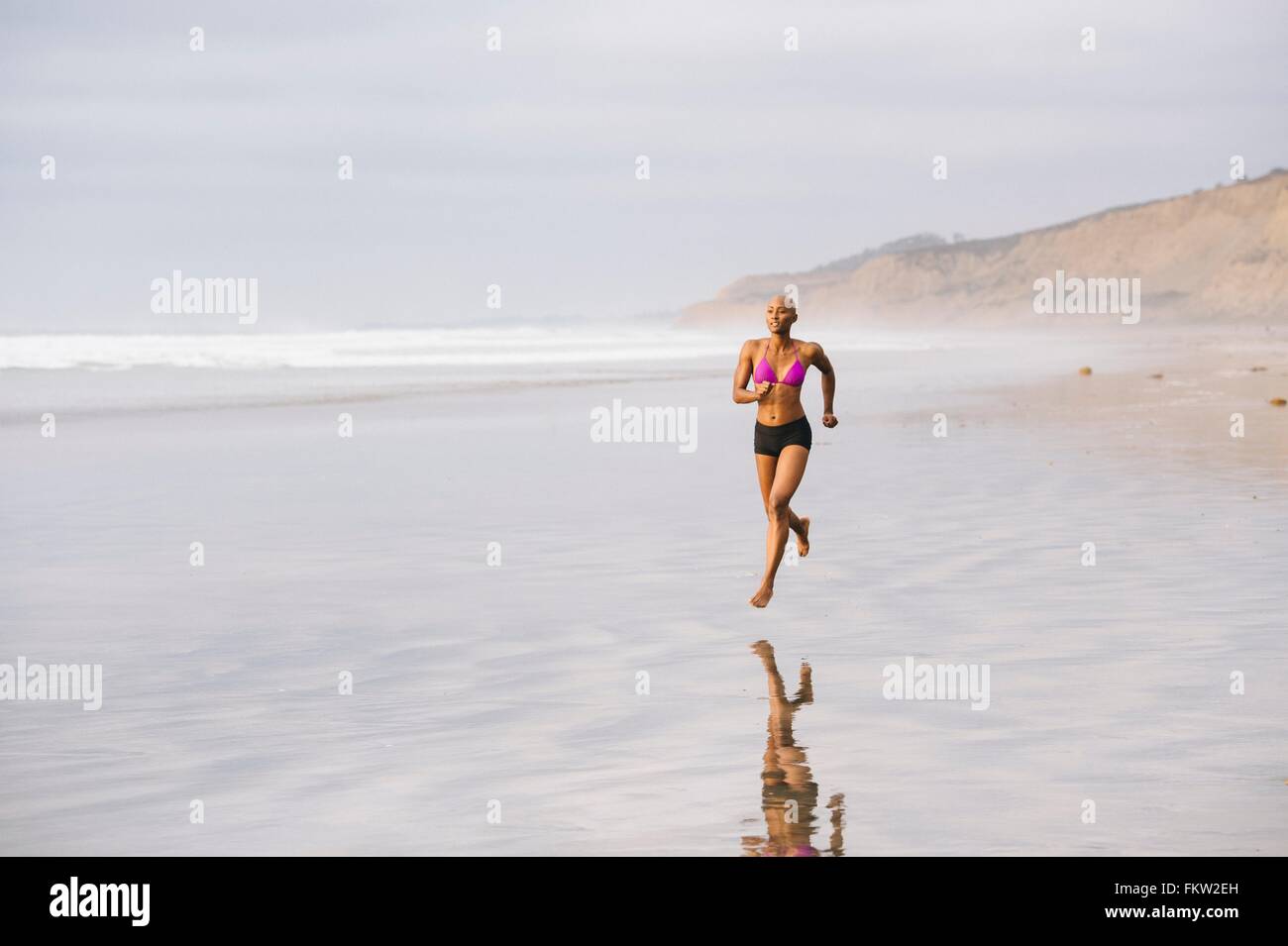 Woman in bikini jogging on beach Stock Photo Alamy