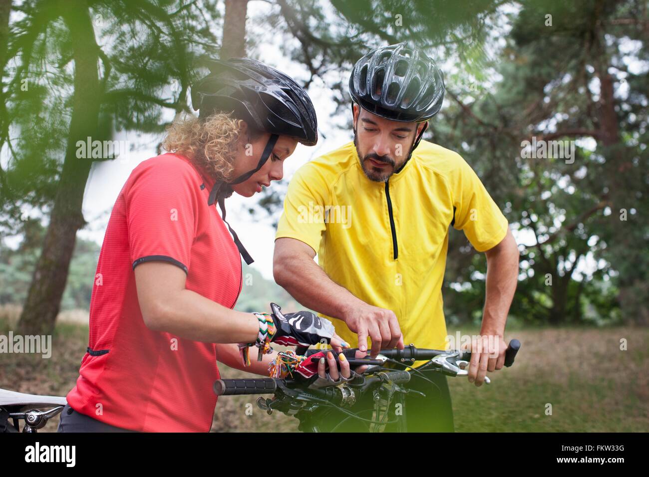 Mountain biking couple checking cycle handlebar in forest Stock Photo ...