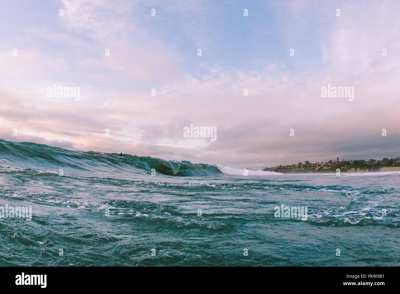 Distant view of surfer on ocean wave near coast, Encinitas, California, USA Stock Photo