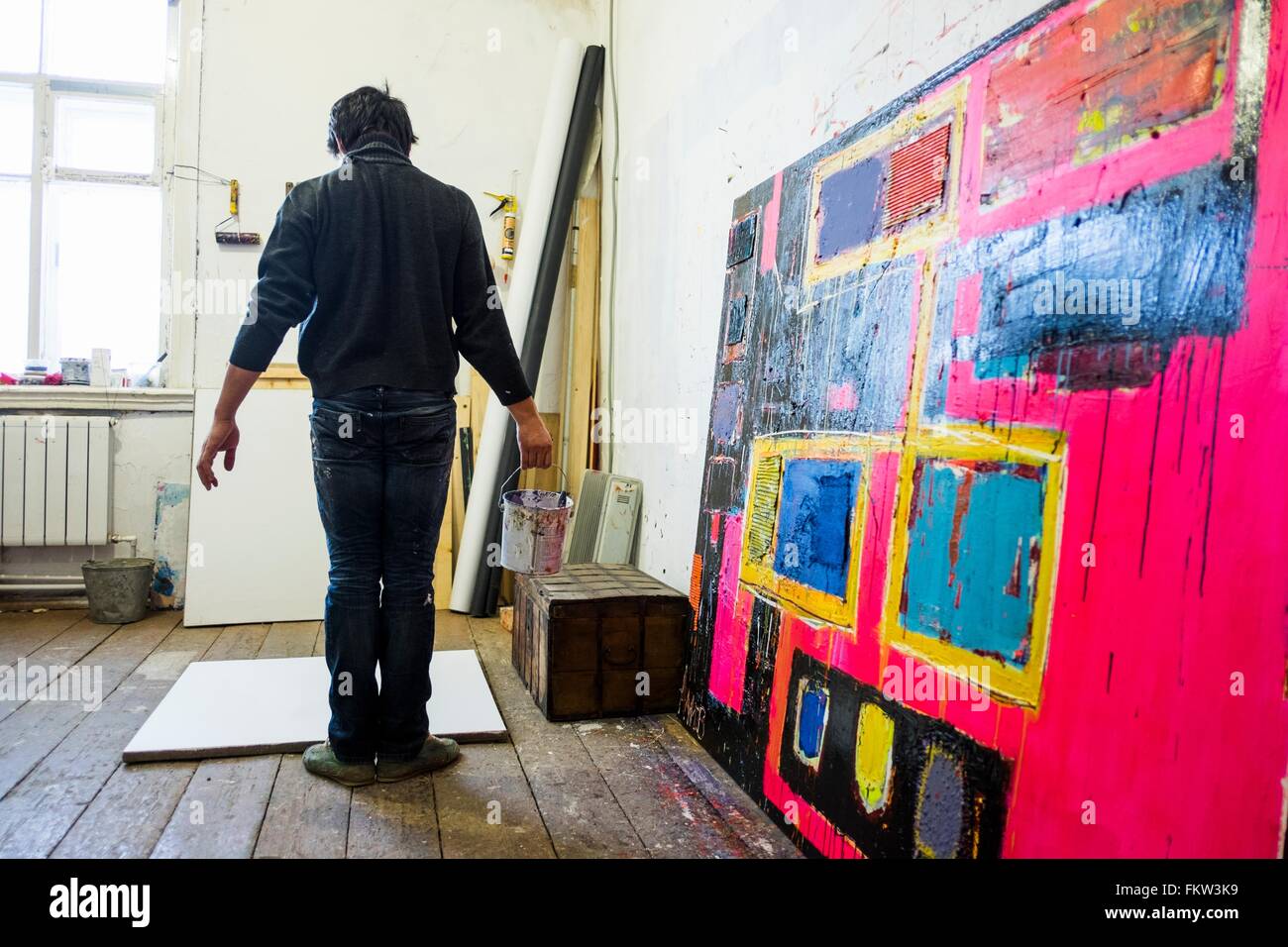 Rear view of male artist standing in front of blank canvas Stock