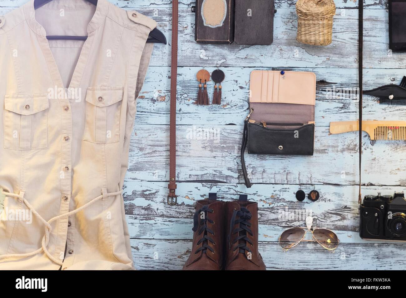 Variety of objects on blue wooden wall including camera, dress and purse Stock Photo