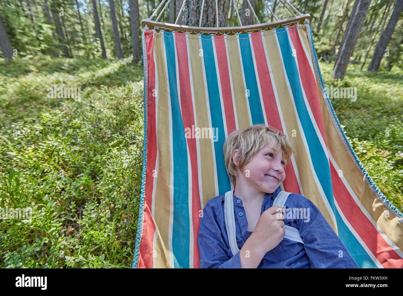 Mischievous boy dressed in retro clothing on forest hammock Stock Photo