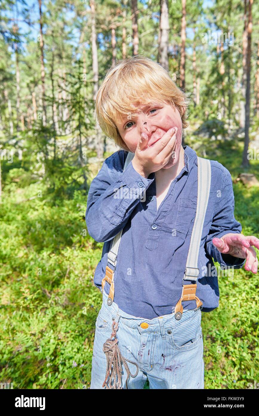 Portrait of young boy wearing retro clothes eating berries in forest Stock Photo