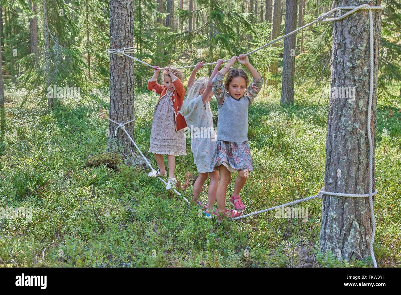 Girls wearing retro clothes balancing on ropes in forest Stock Photo ...