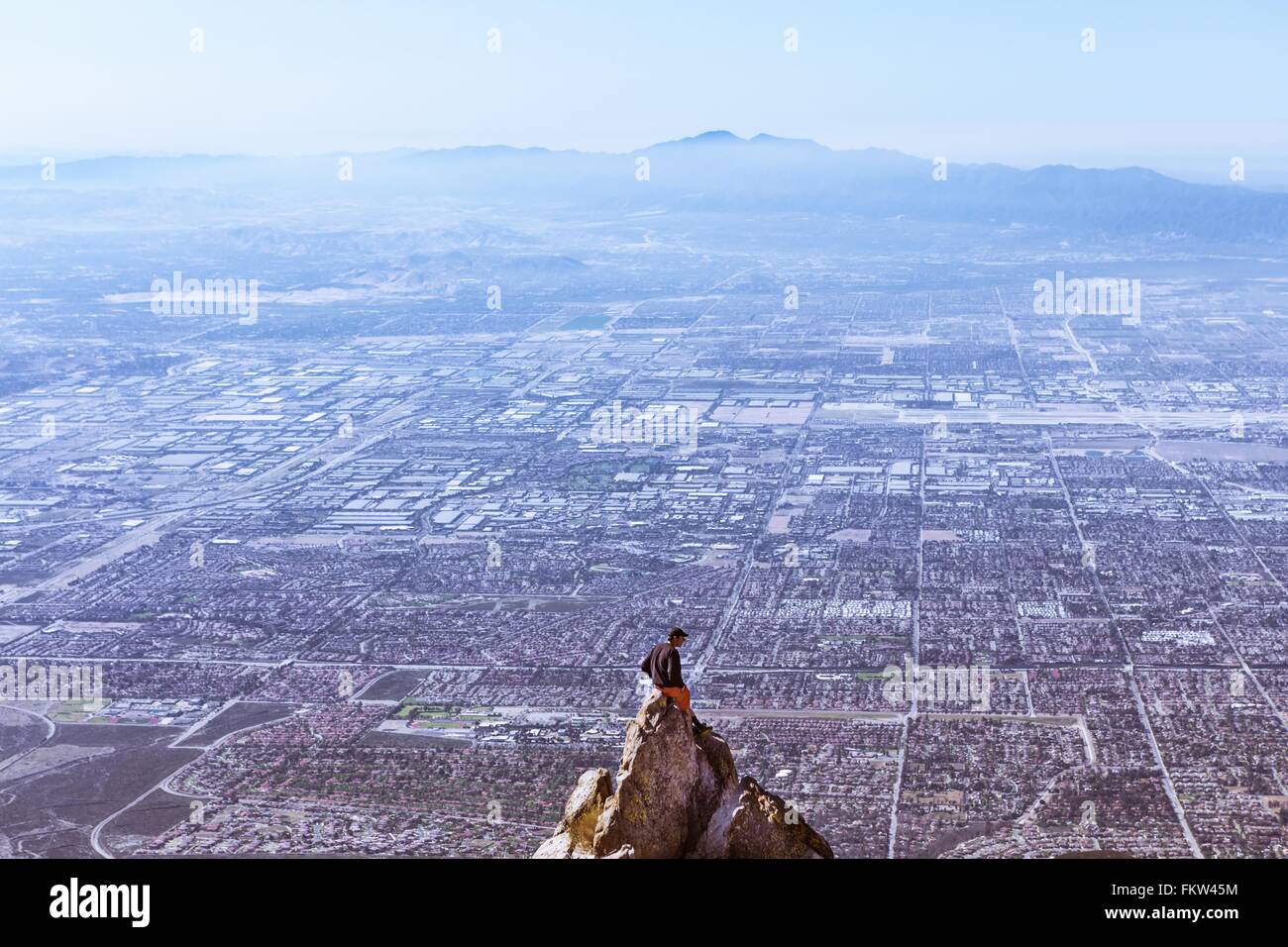 Young man sitting on mountain top, Mount Baldy, California, USA Stock Photo