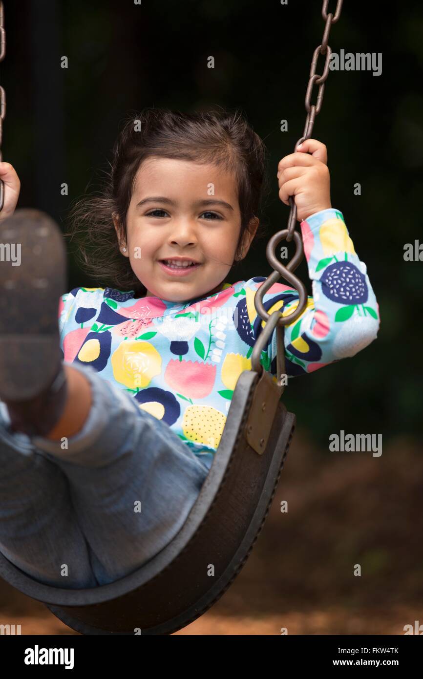 Portrait of girl swinging on playground swing Stock Photo - Alamy