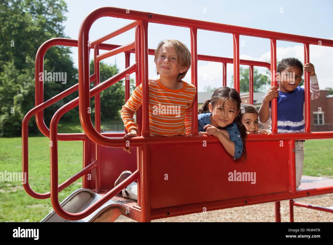 Portrait of four boys and girls on playground slide Stock Photo