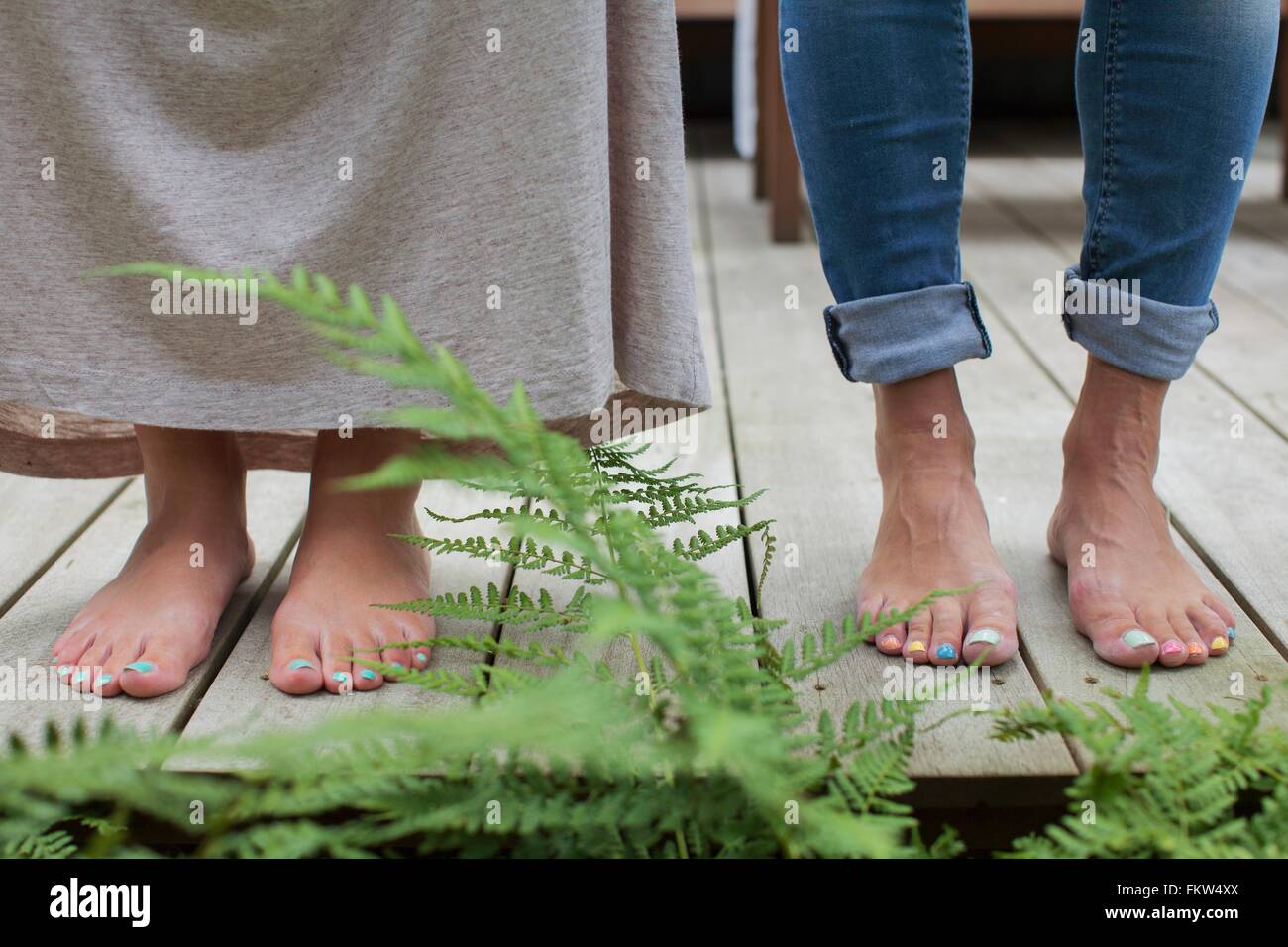 Painted toenails of couple standing on cabin porch Stock Photo