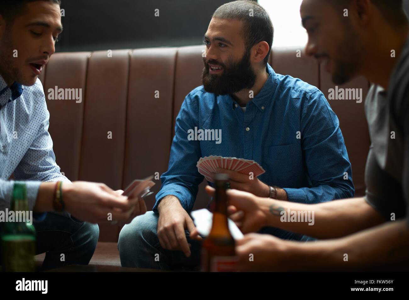 Three young adult male friends playing card game in traditional UK pub Stock Photo