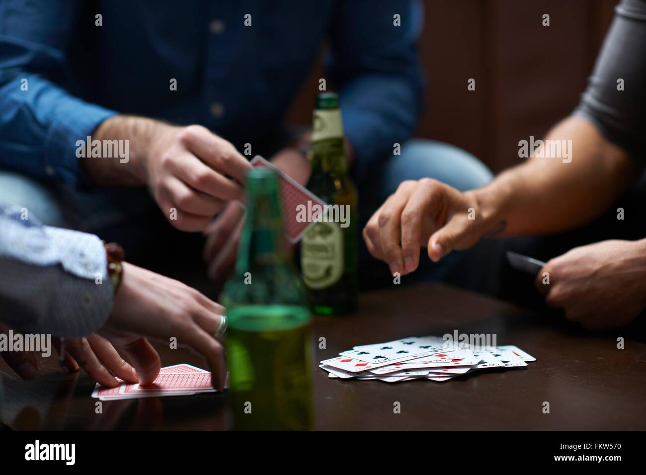 Hands of three men playing card game in traditional UK pub Stock Photo