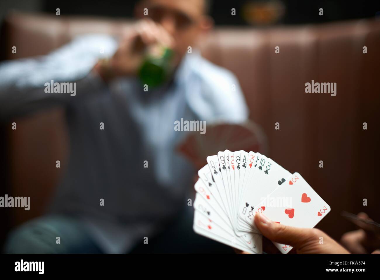 Male hand playing cards in traditional UK pub Stock Photo