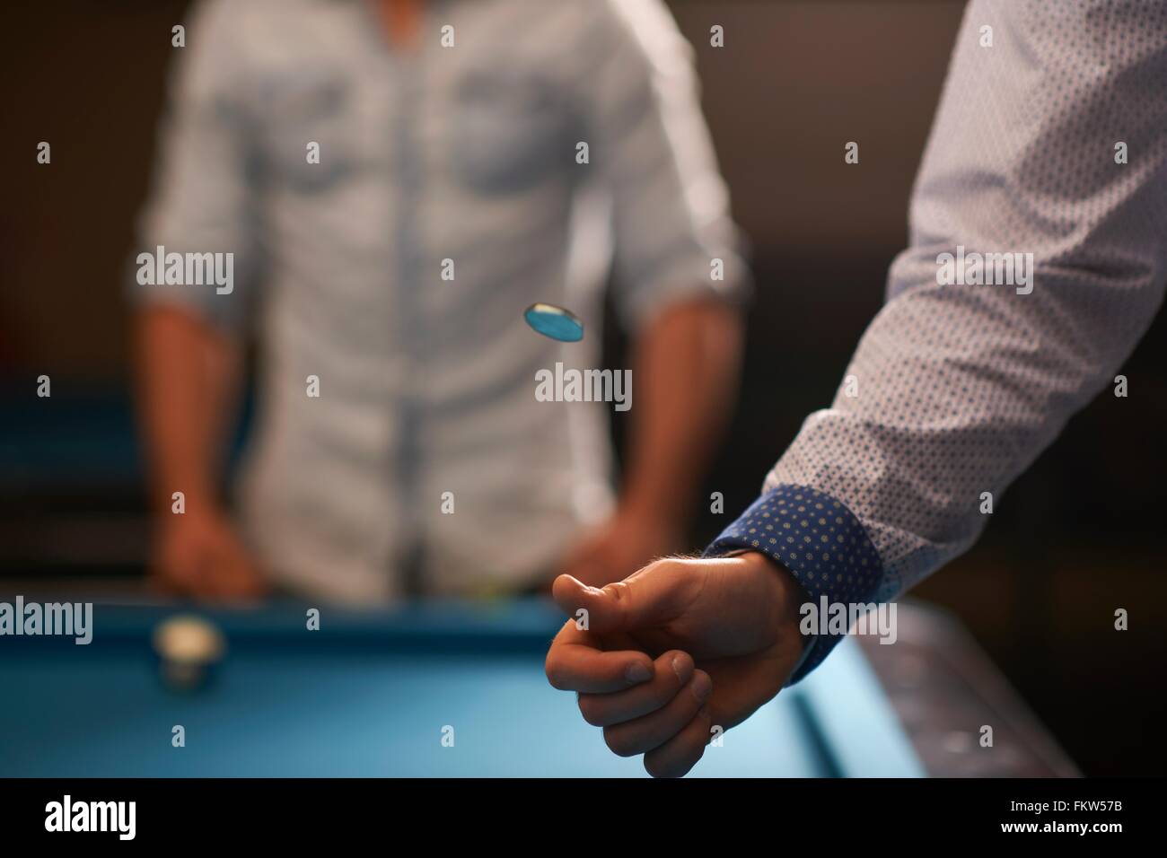 Man tossing coin at pool table Stock Photo