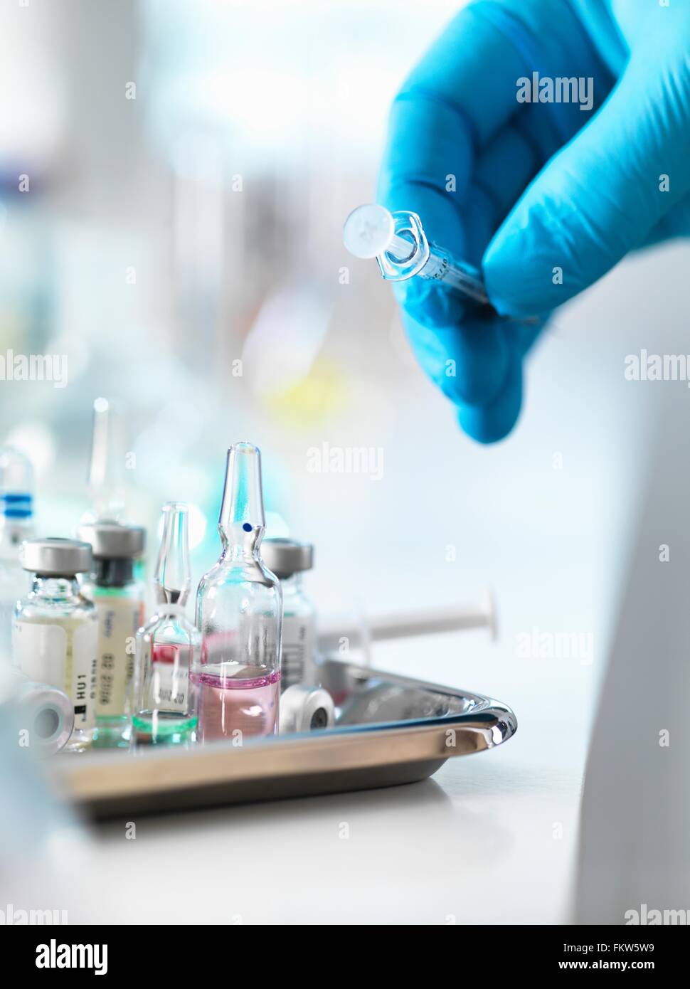 Doctor placing syringe back onto tray with drug vials Stock Photo