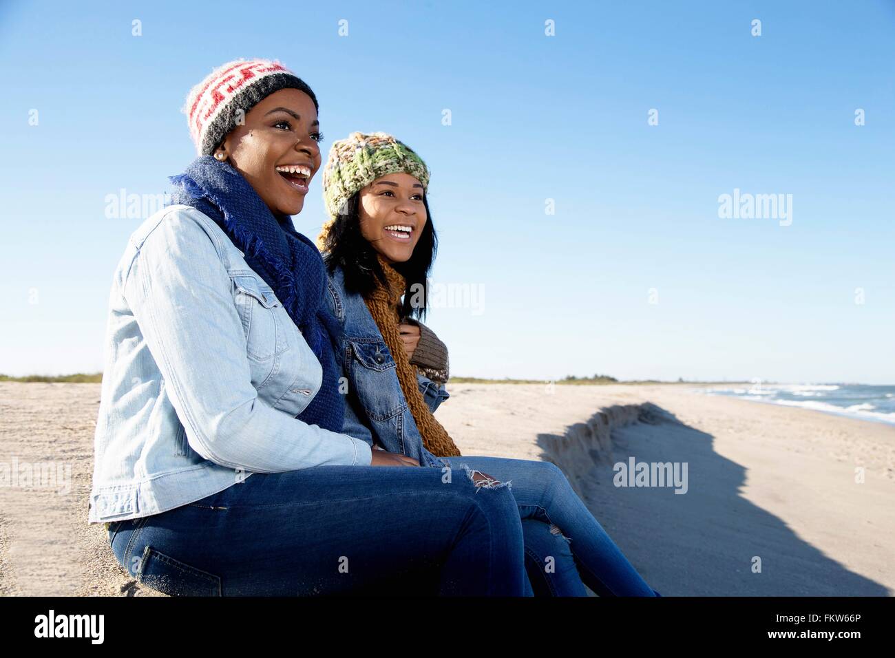 Two female friends relaxing at beach in winter Stock Photo