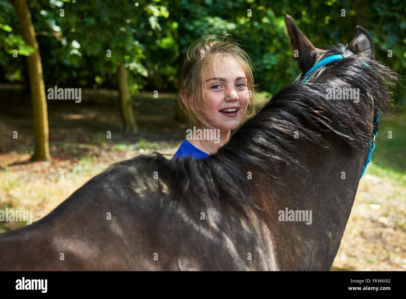 Head and shoulders of girl with horse looking at camera smiling Stock Photo