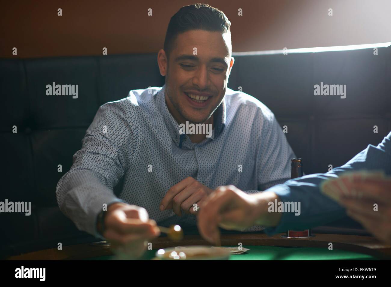 Man gambling key playing card game at pub card table Stock Photo