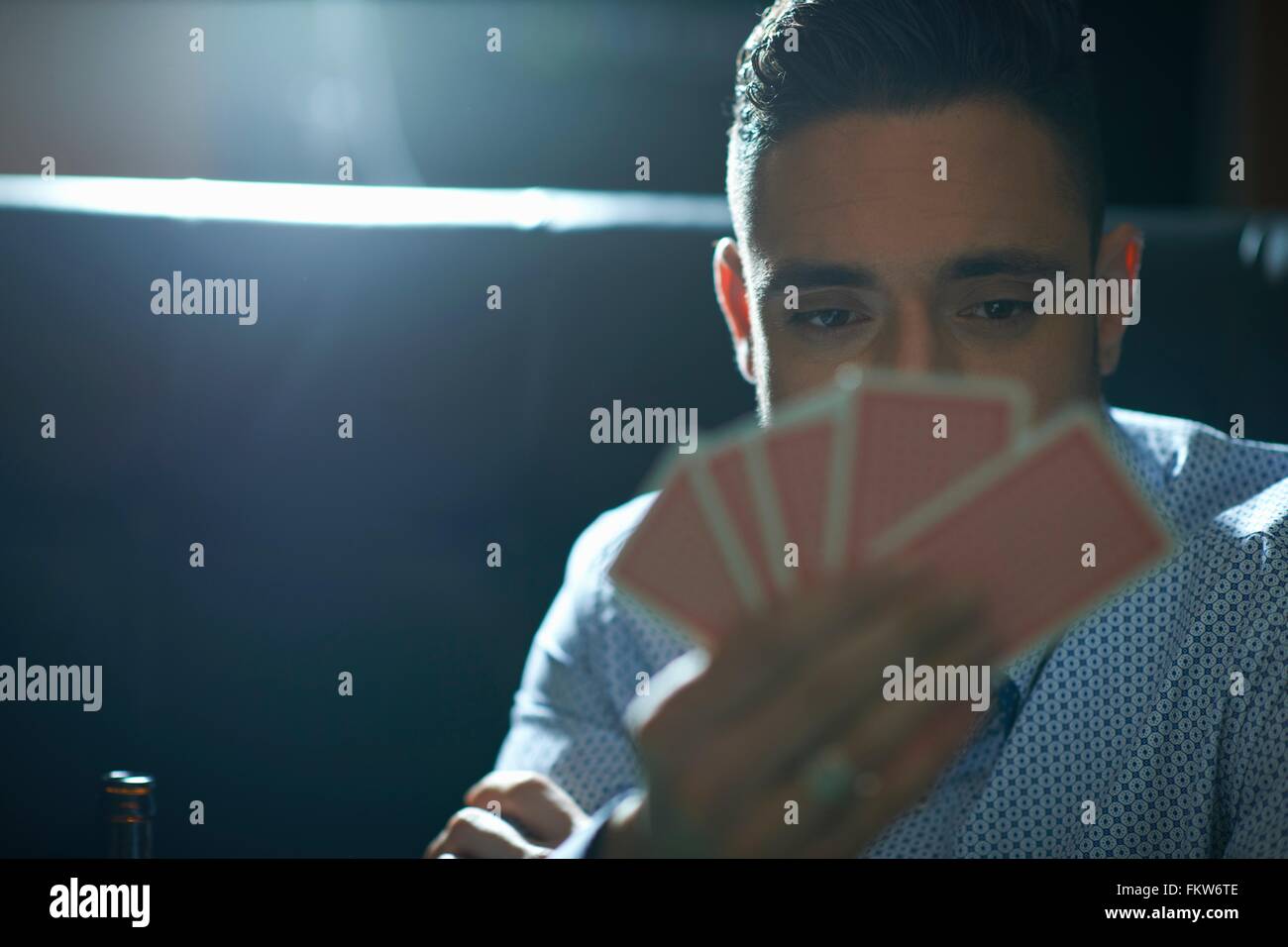 Mid adult man with hand of playing cards playing cards in traditional UK pub Stock Photo