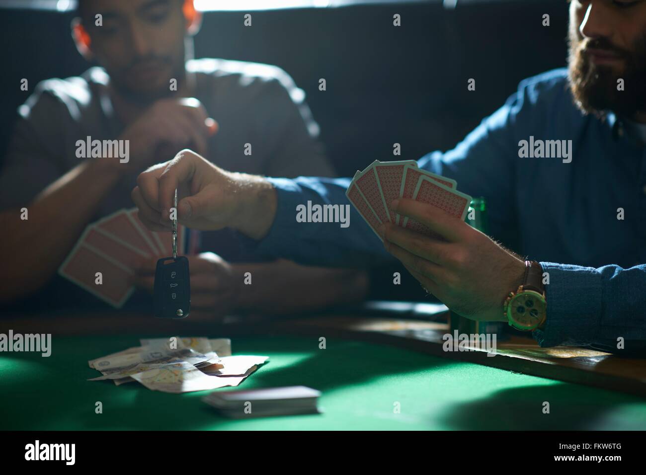 Man gambling car key playing card game at pub card table Stock Photo