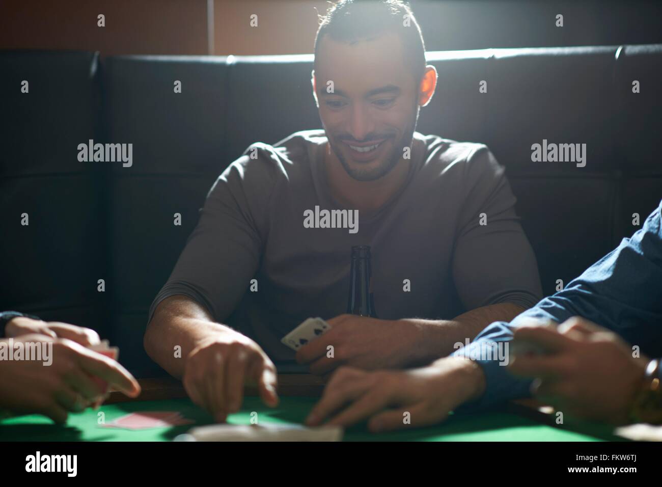 Young man picking up card game winnings at pub card table Stock Photo