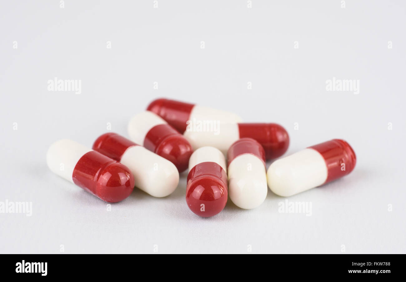 Red and white capsules against a white background Stock Photo
