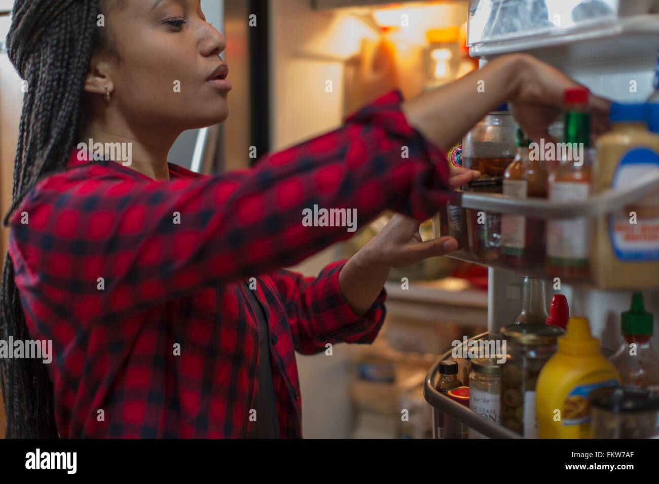 Mid adult woman choosing food from refrigerator in kitchen Stock Photo