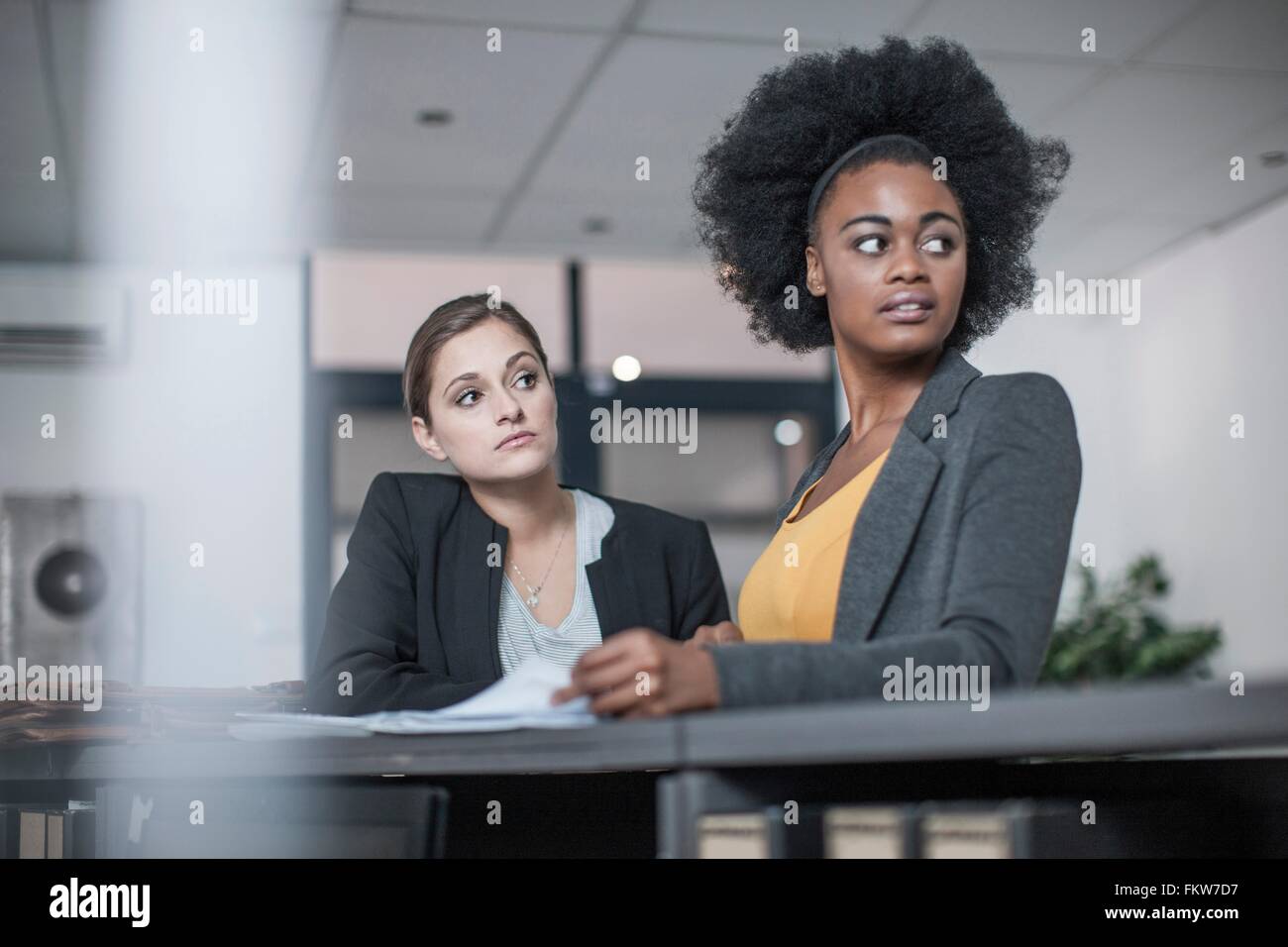 Two young businesswomen distracted at office reception Stock Photo