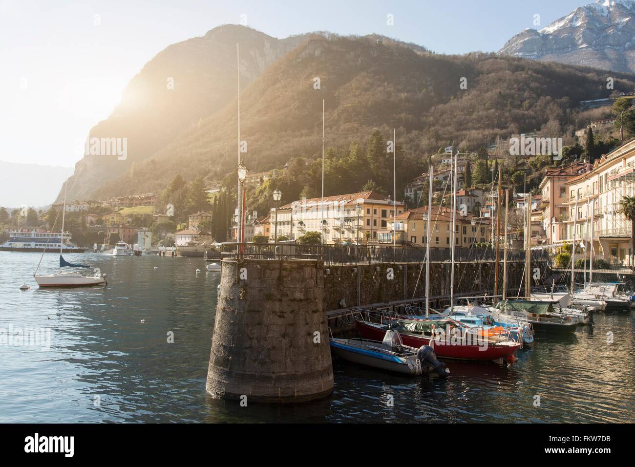 Boats moored in sunlit harbor, Lake Como, Italy Stock Photo