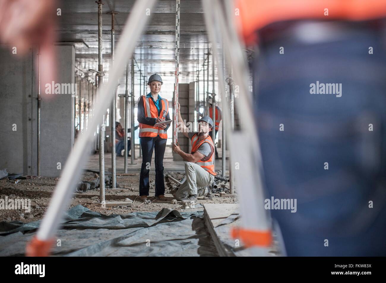 Male and female builders taking measurements for surveyor Stock Photo