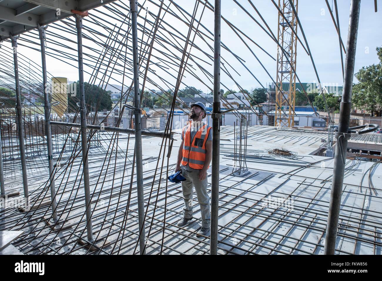 Site manager looking up at steel rod structures on  construction site Stock Photo